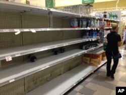 A shopper walks by the empty shelves where bottled water normally would be, at a grocery store in Hollywood, Fla., Oct. 5, 2016.