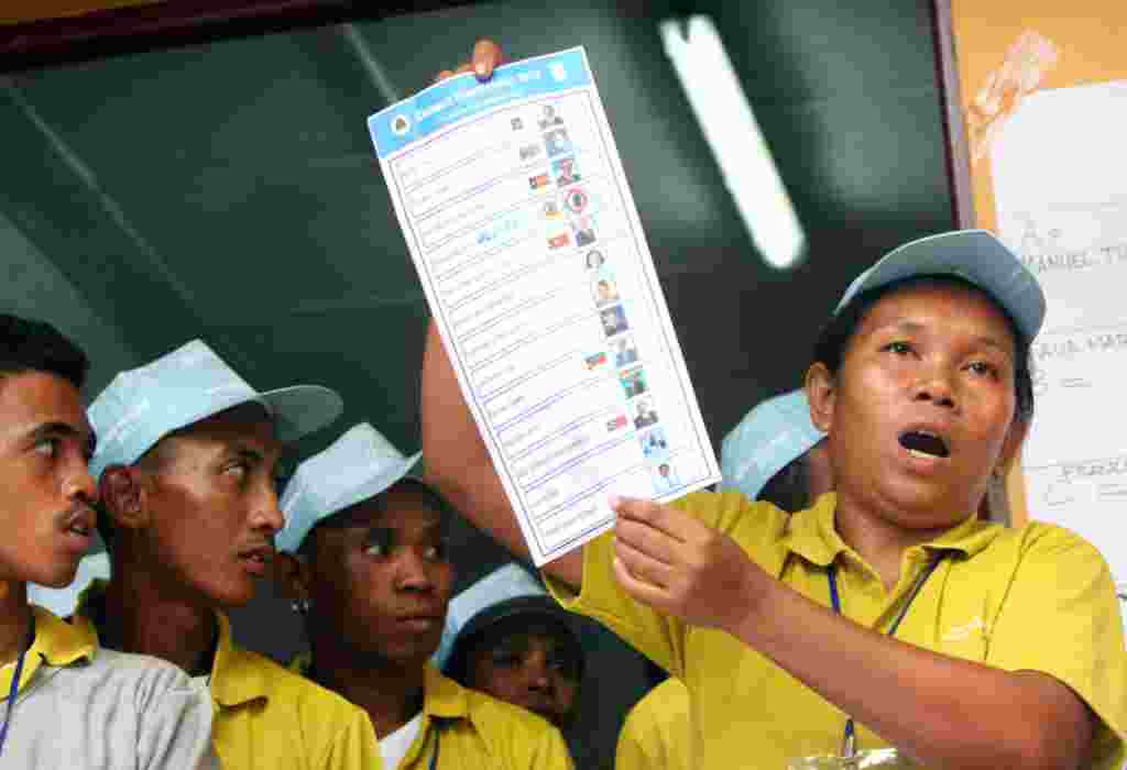Seorang petugas komisi pemilu setempat menunjukkan surat suara saat menghitung perolehan di sebuah TPS di Dili (17/2) (AP).