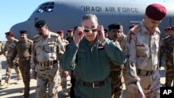 Iraqi Defense Minister Khaled al-Obeidi, center, arrives at a military a base outside Tikrit, 130 kilometers (80 miles) north of Baghdad, Iraq, March 9, 2016. 