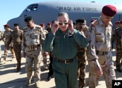 Iraqi Defense Minister Khaled al-Obeidi (c) arrives at a military a base outside Tikrit, 130 kilometers (80 miles) north of Baghdad, Iraq, March 9, 2016.