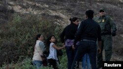 Một nhóm di dân đứng cạnh một nhân viên Kiểm soát Biên giới CBP của Mỹ ở Quận San Diego, ngày 2/12/2018.