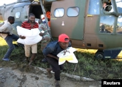 Workers offload food aid from a helicopter in the aftermath of Cyclone Idai, in Buzi, Mozambique, March 25, 2019.