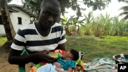 James Harris, the widower of Salome Karwah, feeds his child outside his house in Monrovia, Liberia, March 2, 2017. 