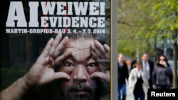 People walk beside an advertising poster for the exhibition 'Evidence' by Chinese artist Ai Weiwei at the Martin-Gropius Bau in Berlin, April 2, 2014.