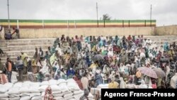 FILE - People who fled the war from May Tsemre, Addi Arkay and Zarima gather around in a temporarily built internally displaced people camp to receive their first bags of wheat from the World Food Program in Debark, Ethiopia, Sept. 15, 2021. 