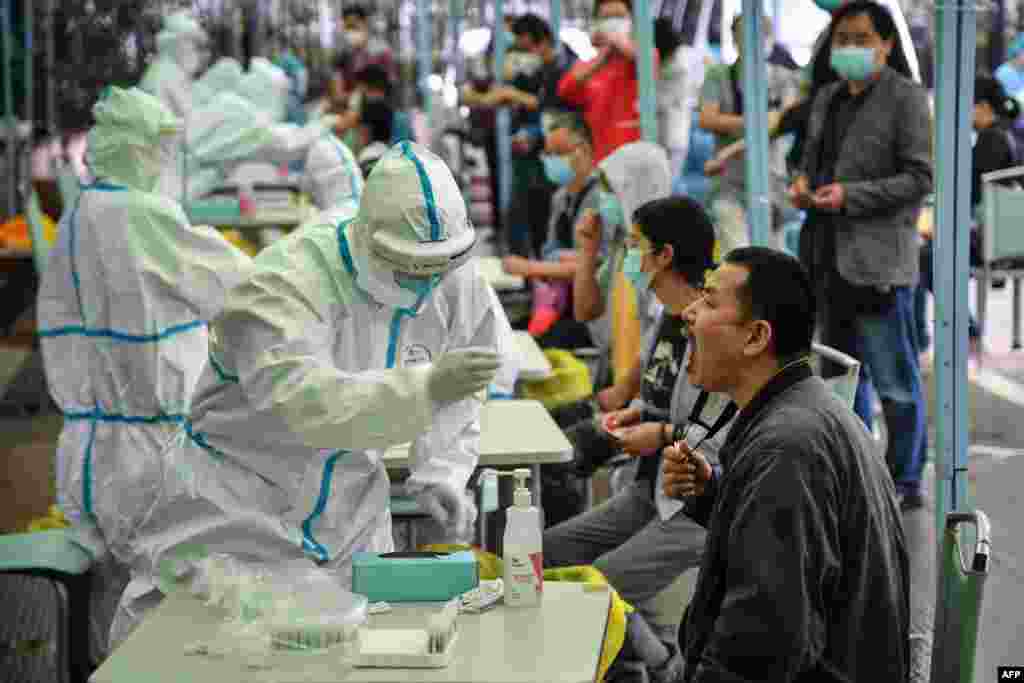 A medical worker takes a sample from a resident to be tested for the COVID-19 in Wuhan in China&#39;s central Hubei province.&nbsp;Nervous residents of the pandemic epicenter lined up throughout the city for testing after reports of new cases led to a mass screening campaign.