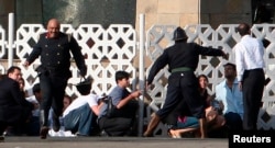 FILE - People run for cover as gunshots are fired from inside the Taj Mahal hotel in Mumbai, Nov. 27, 2008. In 2008, 10 heavily armed gunmen mounted coordinated raids that lasted three days.
