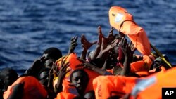 Des migrants lèvent les mains pour recvoir les gilets de sauvetage lors d'une opération de secours de l'ONG Proactive Open Arms dans la Méditerranée, 27 janvier 2017.