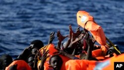 Para migran dari Sub-Sahara Afrika mengacungkan tangan mereka untuk mengambil jaket pengaman, ketika mereka diselamatkan oleh para anggota LSM, Proactive Open Arms, di Laut Mediterania, sekitar 22 mil utara Zumarah, Libya, pada 27 Januari 2017.