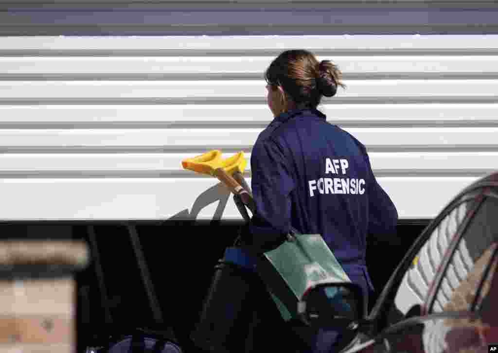 A police investigator arrives with a shovel at a home&nbsp; after about 800 federal and state police officers raided more than two dozen properties as part of the anti-terror operation, at Guildford in suburban Sydney, Sept. 18, 2014. 