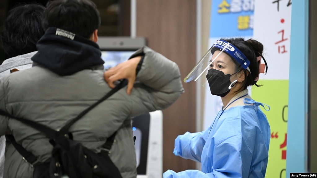 A school teacher wearing protective gear guides a South Korean student before the start of the College Scholastic Ability Test at a high school in Seoul, Nov. 18, 2021. (Jung Yeon-je/Pool Photo via AP)