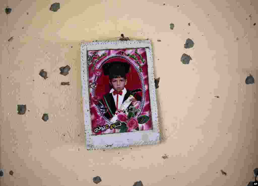 A graduation photo of a Palestinian boy is hung on the wall of a destroyed house in the heavily-bombed Gaza City neighborhood of Shijaiyah, close to the Israeli border, August 1, 2014.