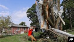 Residentes en Bennet, Nebraska, tratan de desprender la sección lateral de una casa incrustada en un árbol.