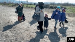 A woman and children cross the Greek-Macedonian border near the town of Gevgelija, Feb. 25, 2016. UNHCR and UNICEF are setting up 20 centers to support and protect children and families as they move across Europe’s migration routes.