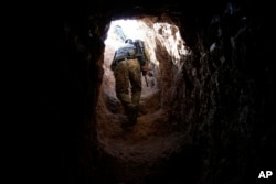 FILE - A fighter walks through a tunnel made by Islamic State fighters, Oct. 18, 2016.