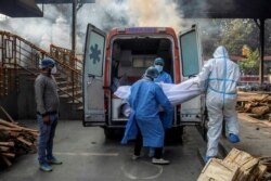 Petugas kesehatan dan kerabatnya membawa jenazah seorang pria yang meninggal karena COVID-19, dari ambulans ke krematorium di New Delhi, India, 13 November 2020. (Foto: REUTERS/Danish Siddiqui)