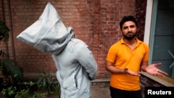 Saud Baloch, 28, a fine art artist, stands near his sculpture called "No Fear" during an interview at the National College of Arts in Lahore, March 22, 2013