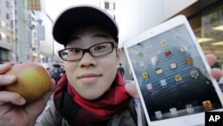 A customer, Koudai Taguchi,19, poses for photographers with Apple's iPad Mini after he bought at a store in Tokyo Friday morning, Nov. 2, 2012.