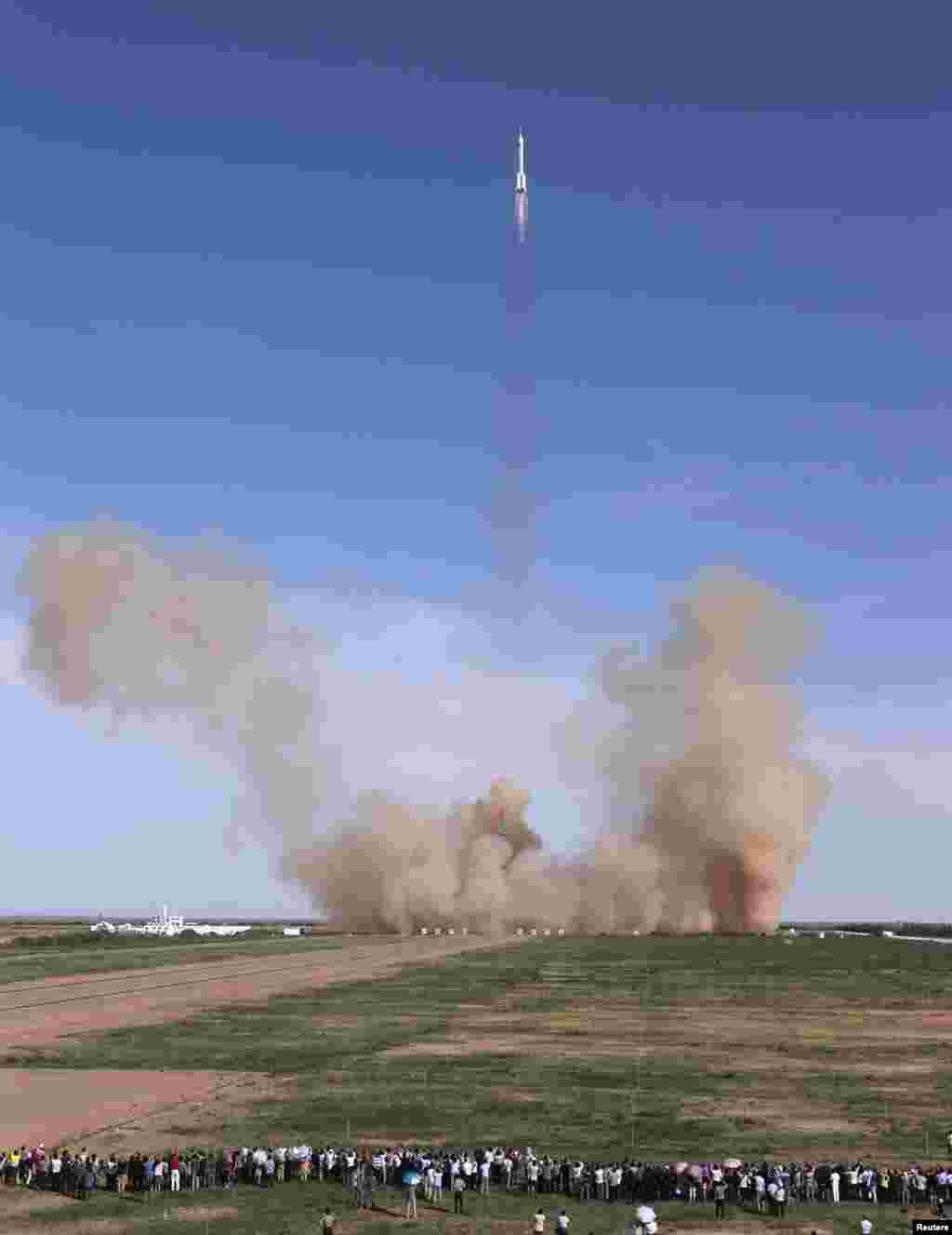 Warga menyaksikan peluncuran roket Long March 2-F yang ditunggangi pesawat luar angkasa berawak Shenzhou-10 dari landasan di Pusat Peluncuran Satelit Jiuquan, provinsi Gansu (11/6). 