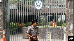FILE - An armed Indonesian police officer stands guard at the gate of the U.S. embassy in Jakarta, Indonesia. 