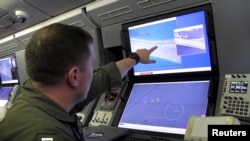 A U.S. Navy crewman aboard a P-8A Poseidon surveillance aircraft views a computer 