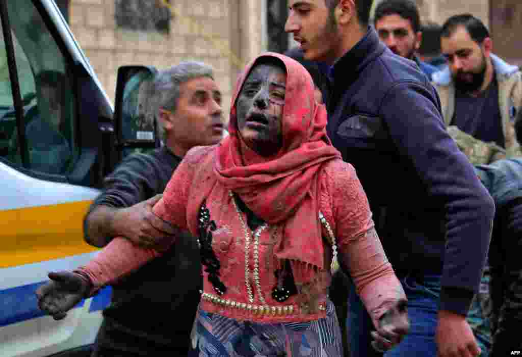 Syrian men help a wounded woman covered in dust following a strike in the town of Khan Shaykhun in the southern countryside of the rebel-held Idlib province.