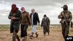 Muškarci, za koje se sumnja da su borci Islamske države, prolaze pored pripadnika Sirijske demokratske snage (SDF) i idu na pretres prije nego napuste posljednje uporište Islamske države, Baghouz, Sirija, 27. februar 2019.