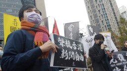 资料照片：一名抗议人士举着“声援香港新闻自由”的标语牌站在中国银行位于台北的分行外。(2021年12月30日)