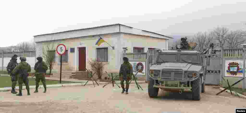 Armed men, believed to be Russian servicemen, stand guard outside a Ukrainian military unit in the village of Perevalnoye, near Simferopol, Crimea, Ukraine, March 11, 2014. 