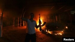 A protester reacts as the U.S. Consulate in Benghazi is seen in flames during a protest by an armed group said to have been protesting a film being produced in the United States September 11, 2012. 