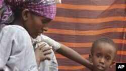 A refugee woman from southern Somalia attends to her malnourished child in their makeshift shelter in a refugee camp in Mogadishu, Somalia, Aug. 6, 2011