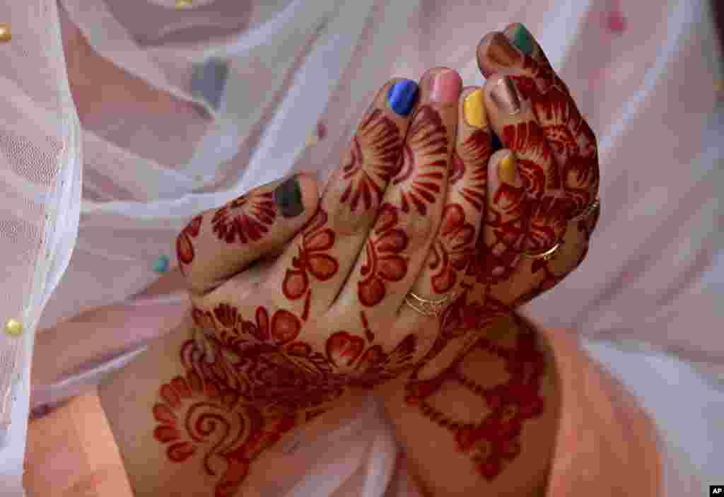 A woman, her hands decorated with traditional henna, prays during Eid al-Fitr prayer at historical Badshahi mosque in Lahore, Pakistan.