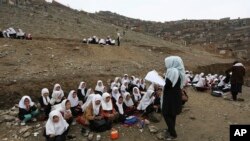 FILE - Afghan students attend school classes in an open-air primary school on the outskirts of Kabul, Afghanistan, April 5, 2017. 