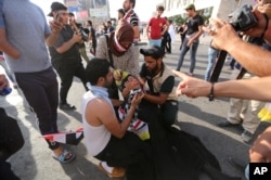 A female protester is assisted after reacting to tear gas fired by security forces in central Baghdad, Iraq, May 27, 2016.