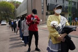 Para pemilih di Korea Selatan mengenakan masker dan antre di tempat pemungutan suara yang digelar di tengah pandemi virus corona, 15 April 2020. (Foto: Reuters)
