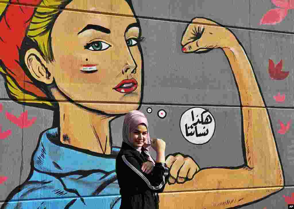 A woman poses for a picture in front of an image with Arabic reading &quot;those are our women&quot; during ongoing protests near Tahrir Square in Baghdad, Iraq.