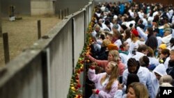 Cắm hoa vào kẻ hở trên Bức tường Berlin để tưởng niệm những người dân Đông Đức đã chết khi tìm cách vượt thoát qua bức tường này tìm tự do.