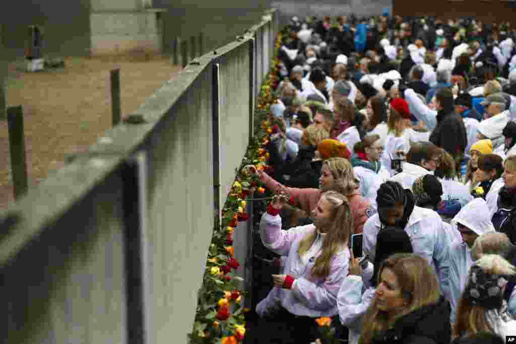 People stuck flowers in remains of the Berlin Wall during a commemoration ceremony to celebrate the 30th anniversary of the fall of the Berlin Wall at Bernauer Strasse in Berlin, Germany, Nov. 9, 2019.