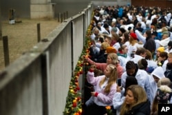 Ljudi stavljaju cvijeće u ostatke Berlinskog zida tokom komemoracije povodom proslave 30. godišnjice pada Berlinskog zida na spomen zidu u Bernauer Strasse u Berlinu, 9. novembra 2019. godine.