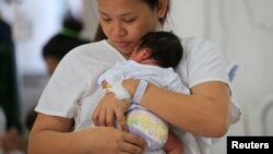 Seorang ibu menggendong bayinya di Rumah Sakit Dr. Jose Fabella Memorial di Quiapo, metro Manila, Filipina, 12 Mei 2018.