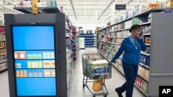 A customer pulls her shopping cart past an information kiosk at a Walmart Neighborhood Market, Wednesday, April 24, 2019, in Levittown, N.Y. (AP Photo/Mark Lennihan)