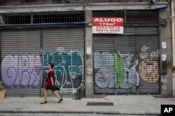 In this May 31, 2017 photo, stores stand shuttered in downtown Rio de Janeiro, Brazil. The sign reads "Rent" in Portuguese.