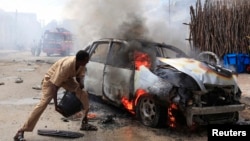 A man tries to extinguish a burning car after it exploded near Hamaerweyne market in Mogadishu, Somalia, July 24, 2013. 