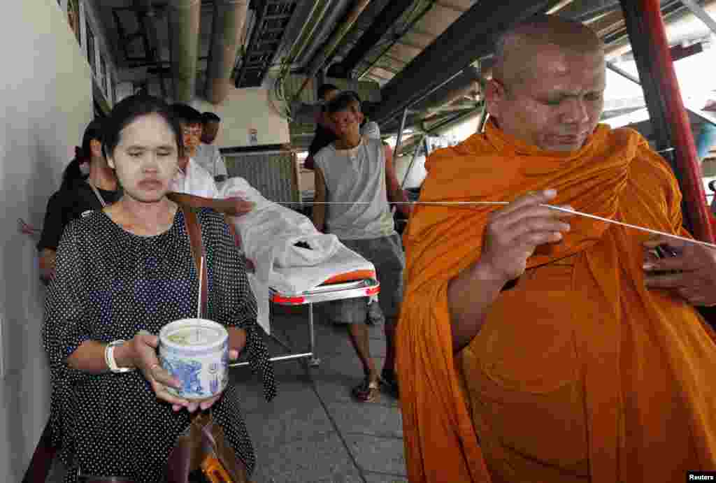 A Buddhist monk and Tipyao Choochan, whose husband was killed when a grenade was thrown at protesters January 17, takes part in a traditional Buddhist ceremony in Bangkok, Thailand, Jan. 19, 2014. 