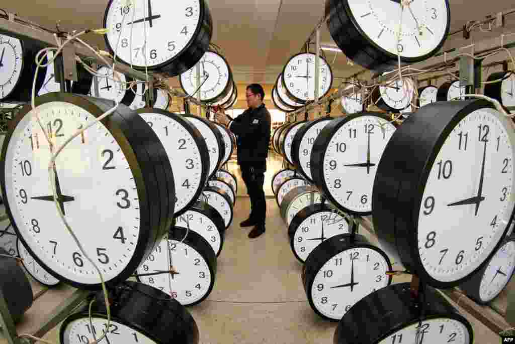 A technician checks hanging clocks at a clock company in Yantai, in eastern China&#39;s Shandong province.