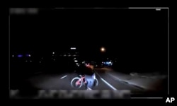 FILE- This file image made from video March 18, 2018, of a mounted camera provided by the Tempe Police Department shows an exterior view moments before an Uber SUV hit a woman in Tempe, Ariz. In a preliminary report on the crash released May 24, 2018, federal investigators said the autonomous Uber SUV spotted the woman about six seconds before hitting her, but didn’t stop automatically because emergency braking was disabled.