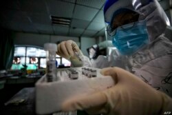 En esta foto tomada el 10 de marzo de 2020, se ve a personal médico sosteniendo muestras de pacientes infectados con el nuevo coronavirus en un hospital de la Cruz Roja en Wuhan, China.
