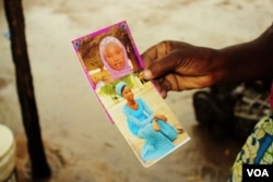Esther Yakubu hold a photo of her daughter, Dorcas Yakubu, the Chibok girl who was featured in the Boko Haram video that was released today in Abuja, Nigeria, Aug. 13, 2016. (C. Oduah/VOA)