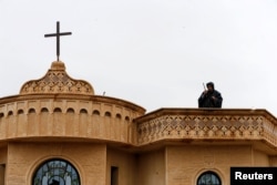 A security member stands guard on the top of a church during a mass on Christmas Eve at the Mar Shimoni church in the town of Bartella, east of Mosul, Iraq, Dec. 24, 2016.