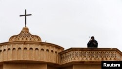 Seorang anggota keamanan berjaga di atas sebuah gereja selama misa pada Malam Natal di gereja Mar Shimoni di kota Bartella, timur Mosul, Irak, 24 Desember 2016. (Foto: Reuters)